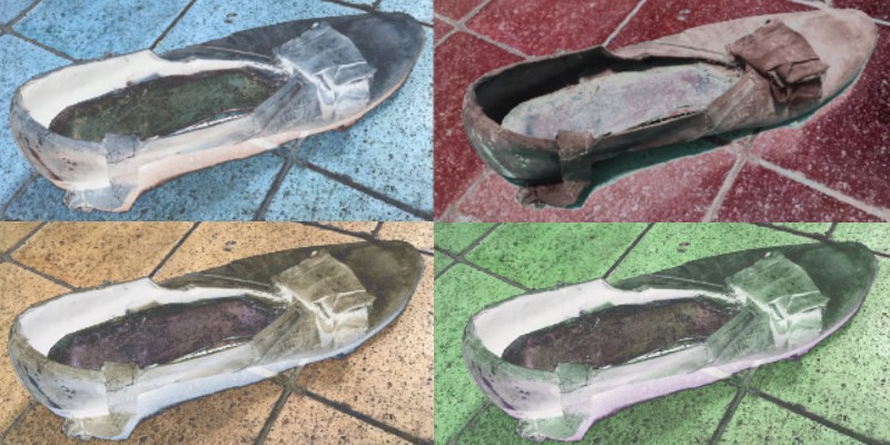 A pop-art style of an old shoe with crushed bow on its toe. The image is split into four sections with different coloured backgrounds; the top left is blue, the top right is red, bottom left is yellow and bottom right is green. The shoe itself has been inverted to a grey colour, as has the outline of the tiled floor it is on.